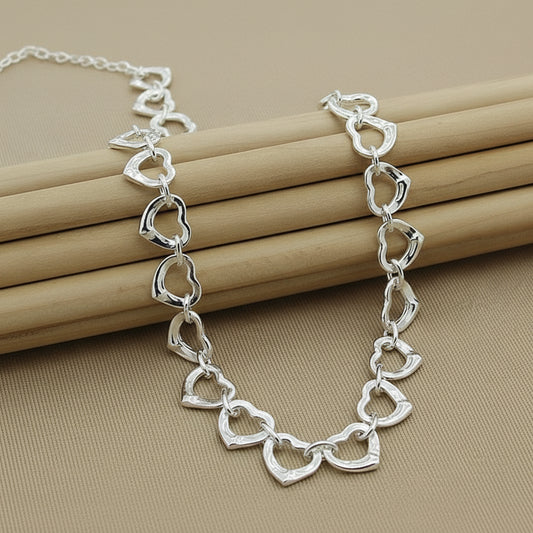 Silver heart-shaped chain bracelet on a beige background