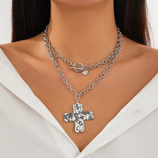 Silver chain necklace with a cross pendant worn by a person