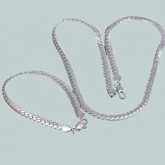 Silver chain necklace on a light light blue background.