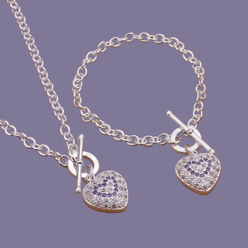 Silver necklace and bracelet set with heart-shaped charms on a purple background