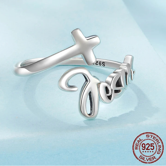 Silver ring with cross and 'Jesus' engraving on a light blue background