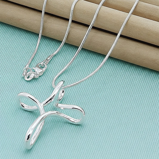Silver cross pendant necklace on a blue green fabric background