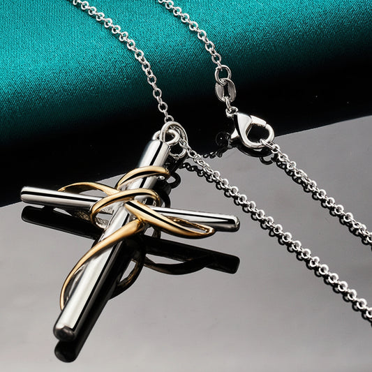 Silver and gold cross pendant necklace on a reflective surface.