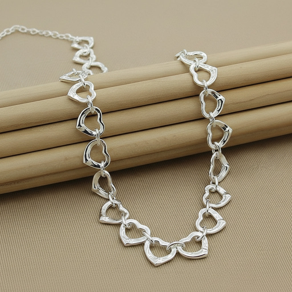 Silver heart-shaped chain bracelet on a beige background