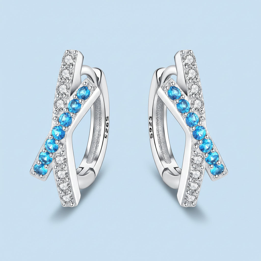 Silver earrings with blue gemstones on a light blue background