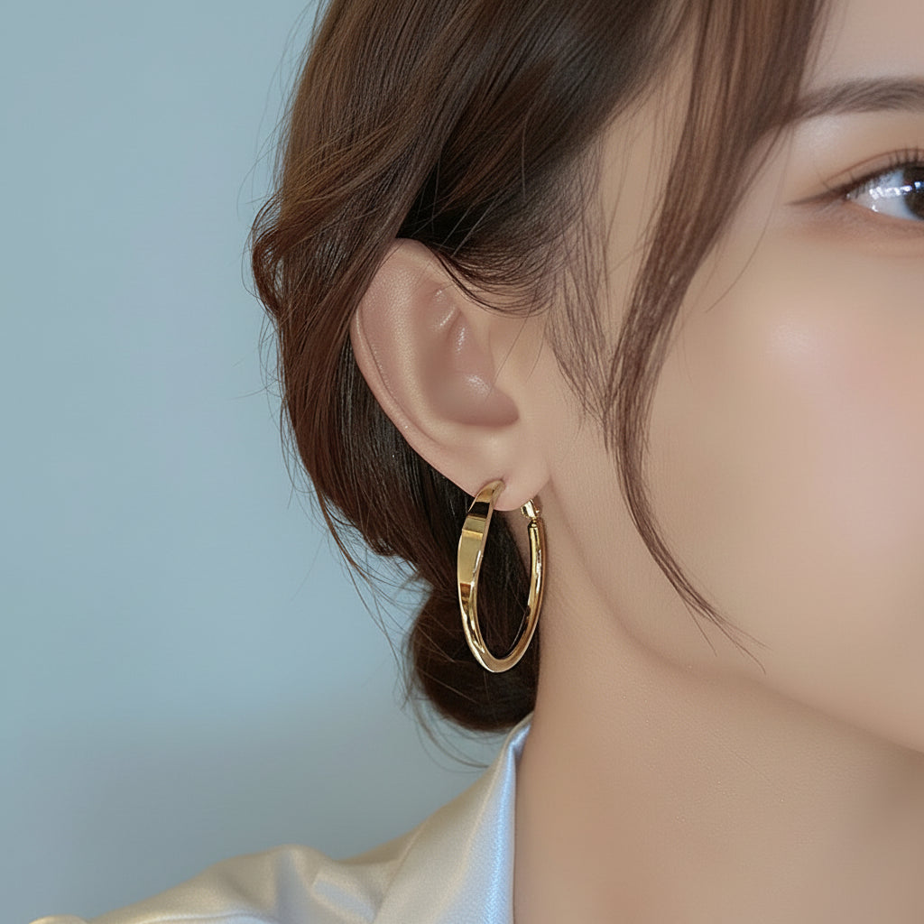 Gold hoop earring worn by a person with a light blue background
