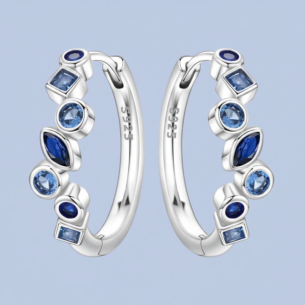 Silver hoop earrings with blue gemstones on a ight blue background