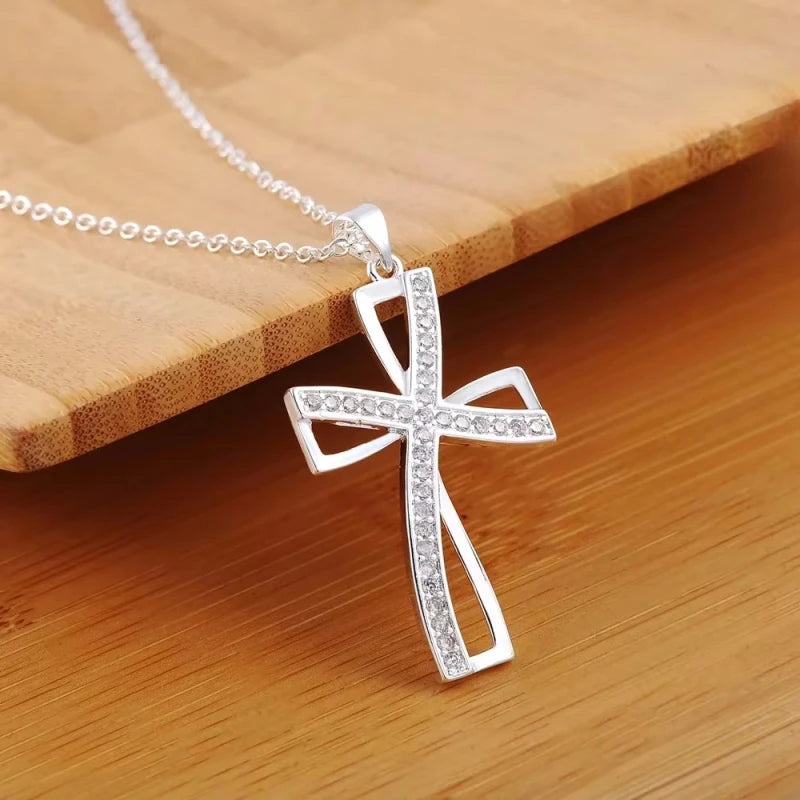 Silver cross pendant necklace on a wooden surface