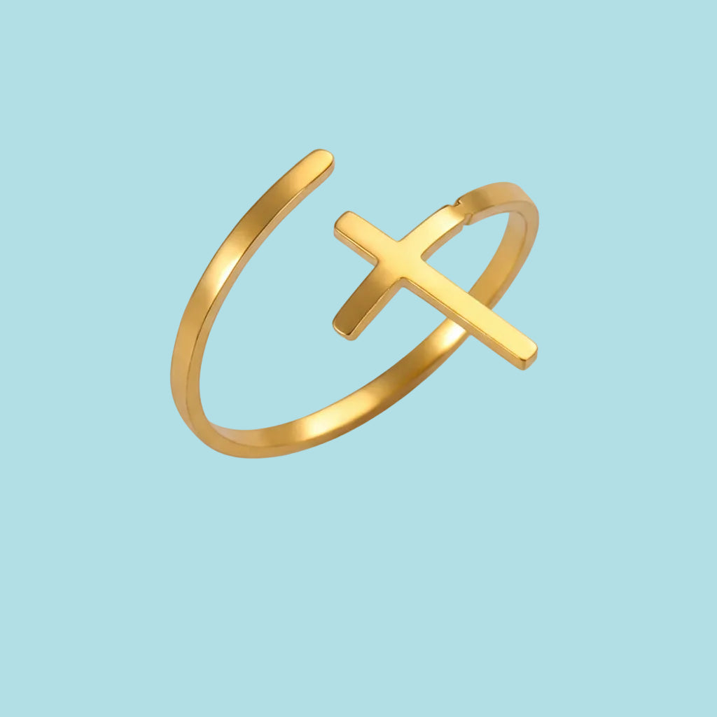 Gold ring with cross design on a white background