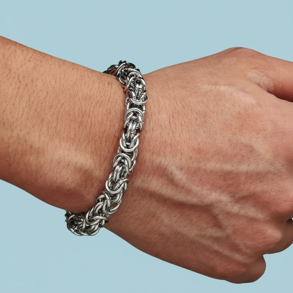 Silver chain bracelet on a wrist against a light blue background