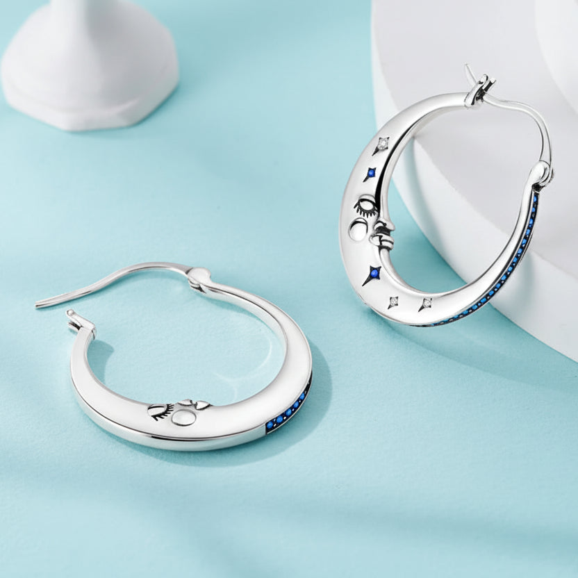 Silver hoop earrings with blue stones on a light gray background