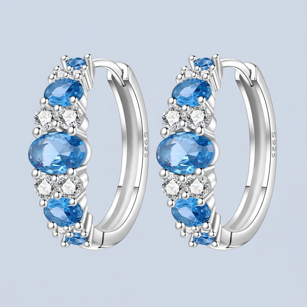 Silver hoop earrings with blue light blue backgroundgemstones and clear stones on a 