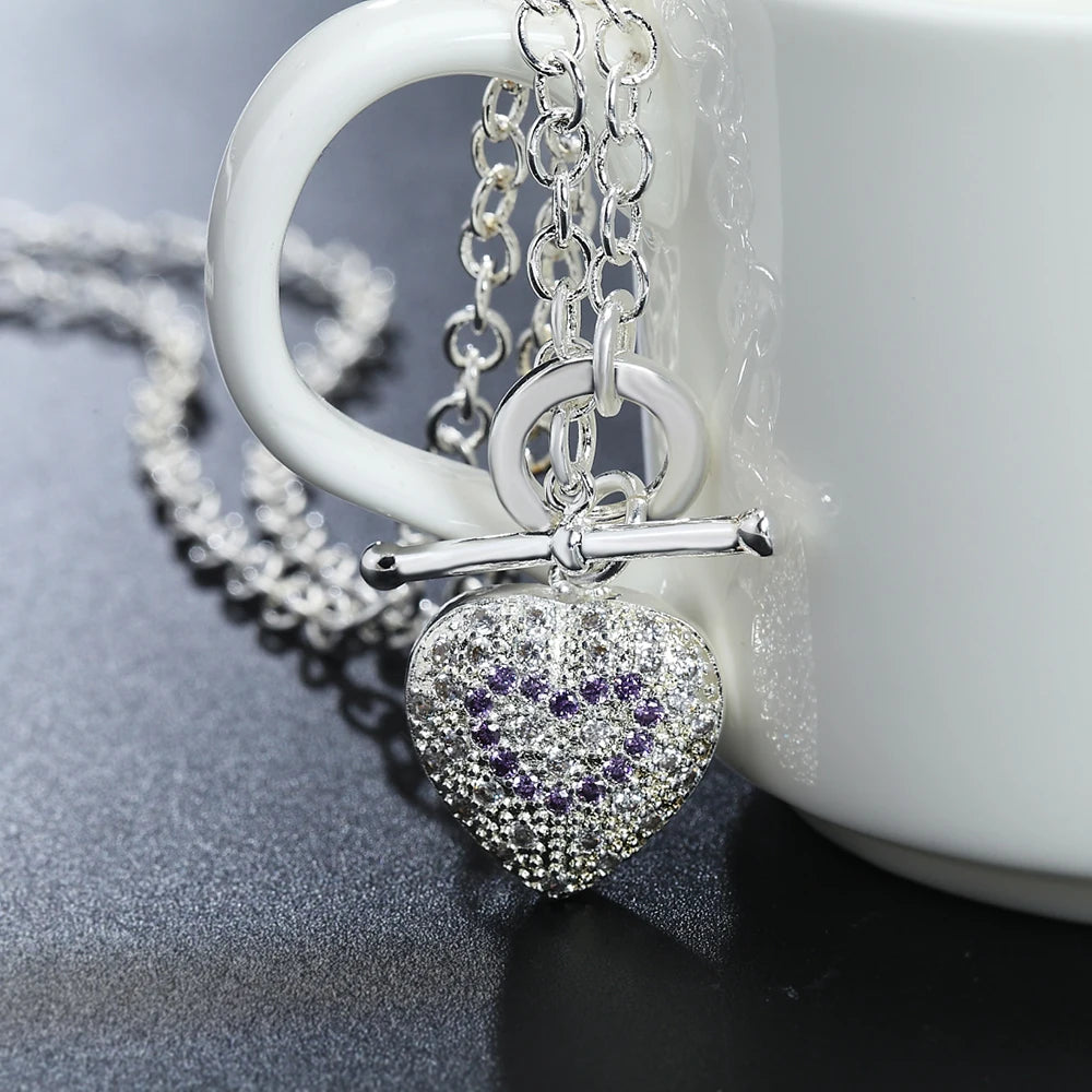 Silver necklace with a heart pendant on a white mug