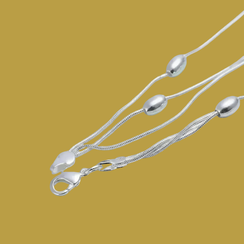 Silver necklace with a clasp on a tan surface