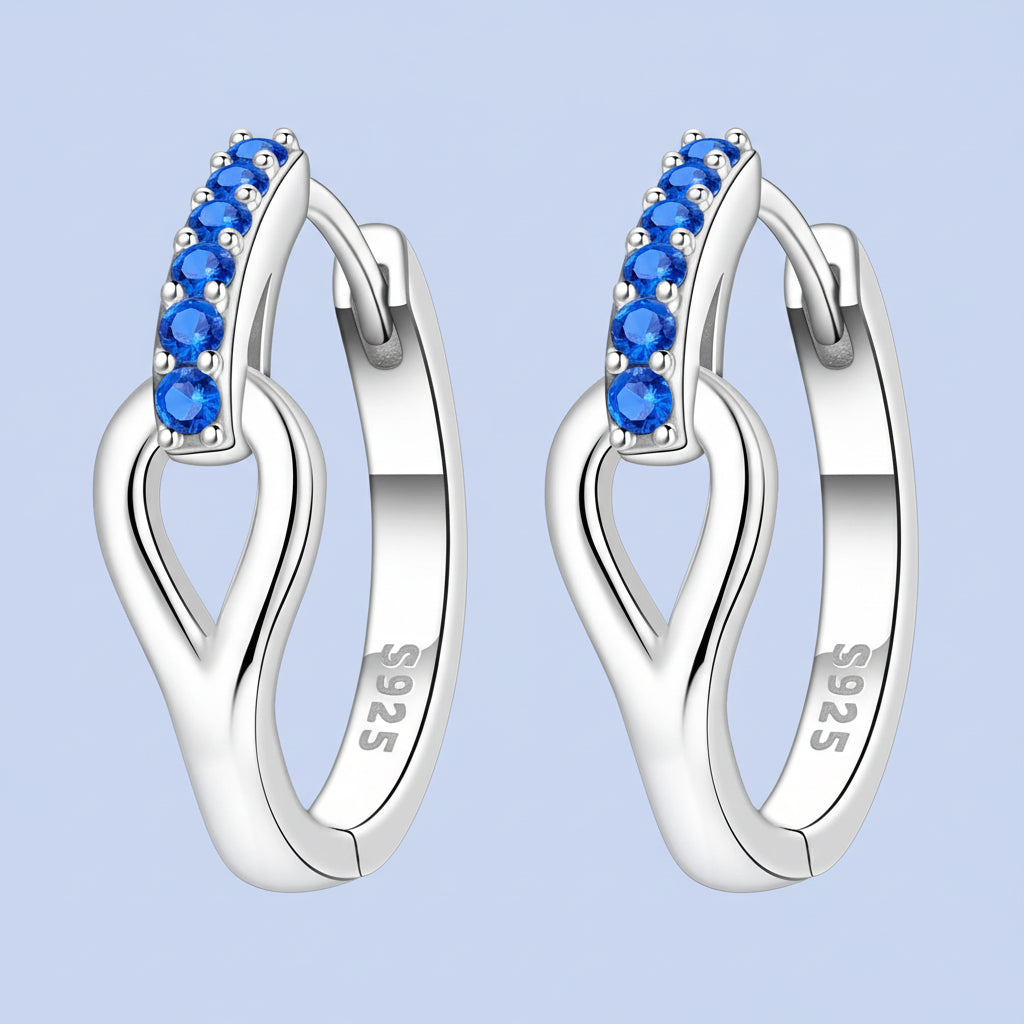 Silver hoop earrings with blue gemstones on a light blue background