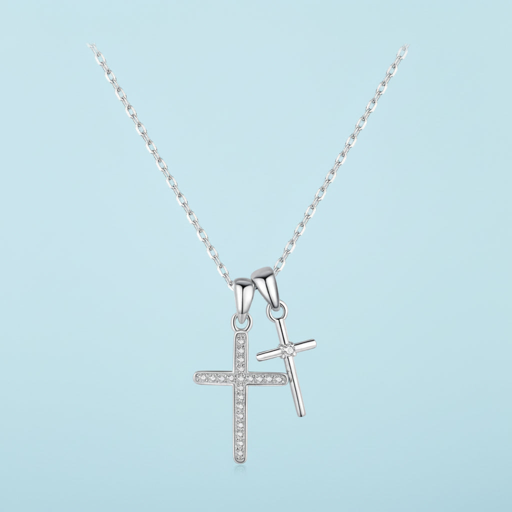 Silver cross pendant necklace on a light blue background.