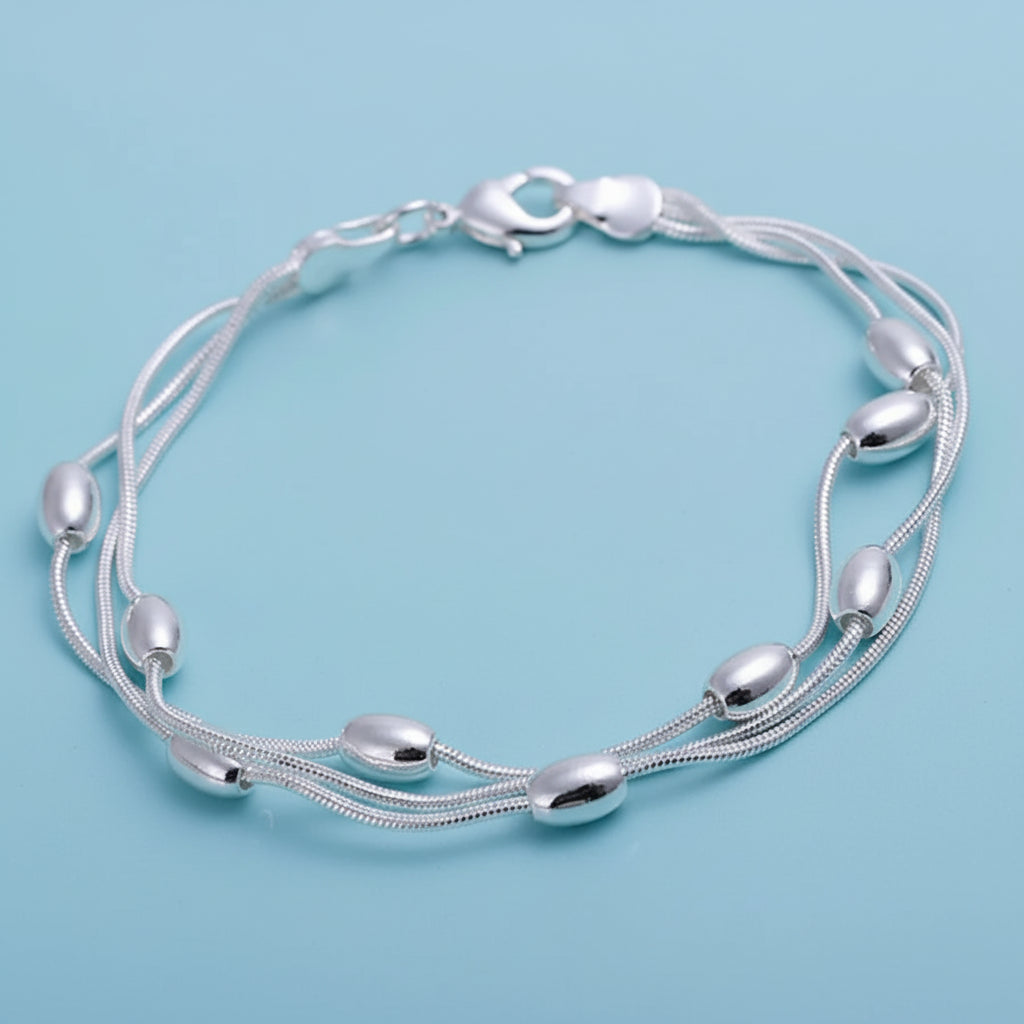 Silver bracelet with multiple strands on a light blue background. 