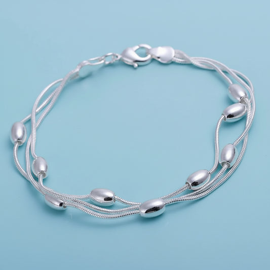 Silver bracelet with multiple strands on a light blue background. 