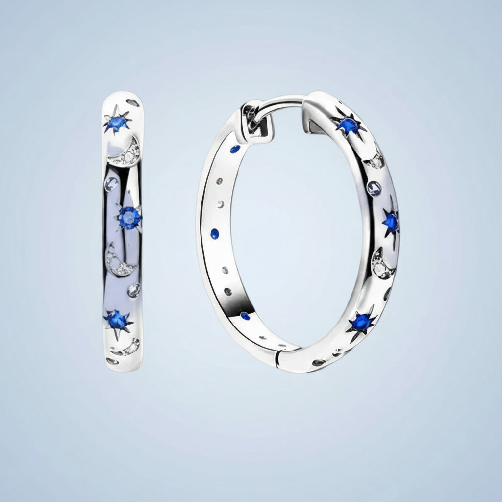Silver hoop earrings with blue gemstones on a light blue background