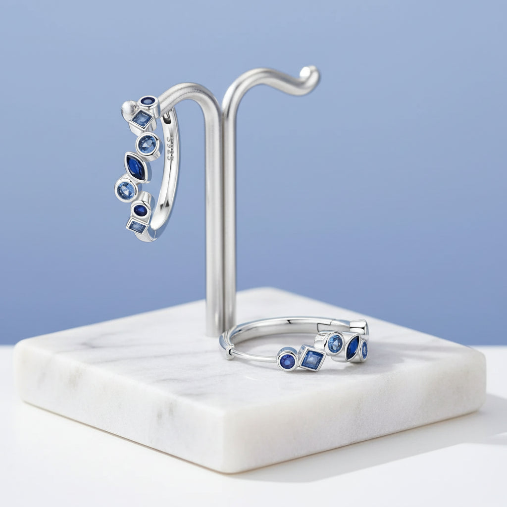 Silver hoop earrings with blue gemstones on a light background