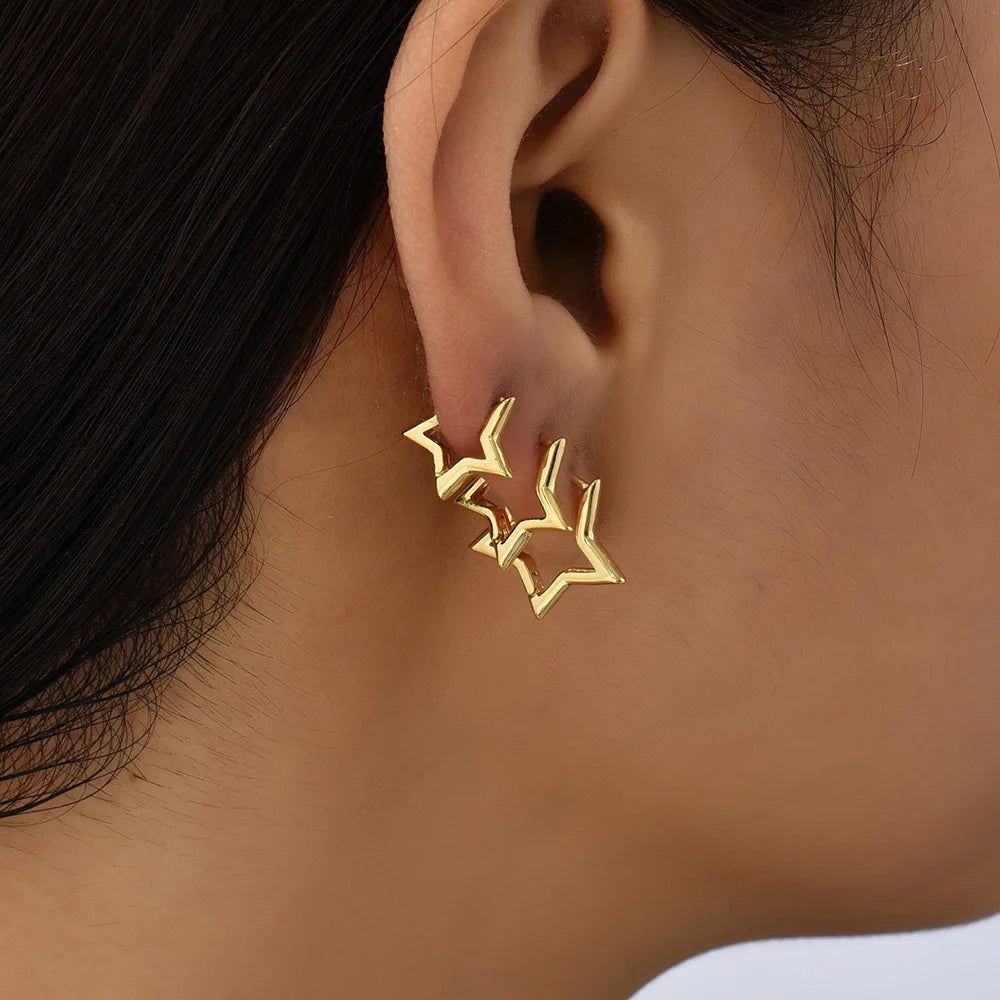 Gold star-shaped earring worn by a person with dark hair.