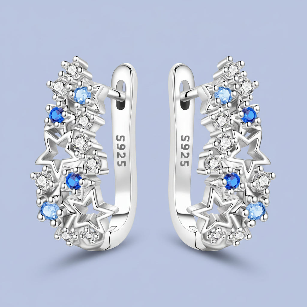 Silver hoop earrings with star designs and blue gemstones on a light blue background
