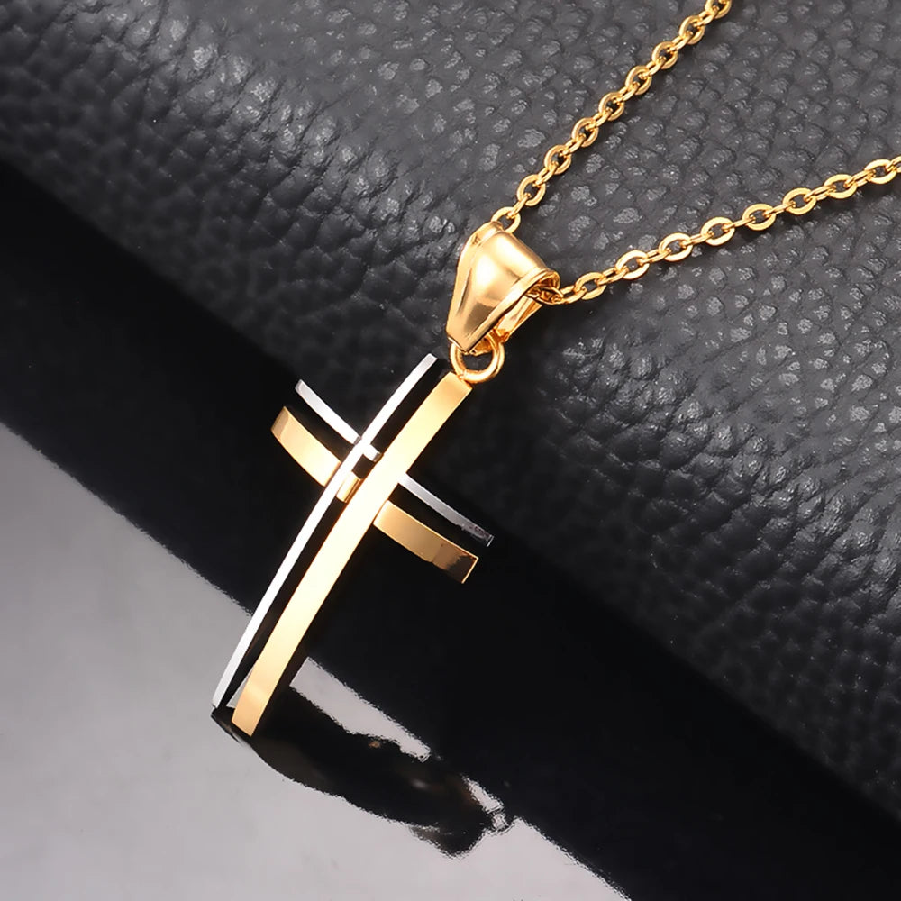 Gold cross pendant necklace on a textured black surface