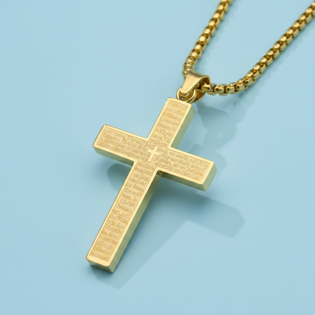 Gold cross pendant with engraved text on a light blue surface