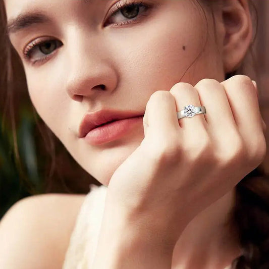 Close-up of a woman wearing a silver ring with a diamond on a blurred background