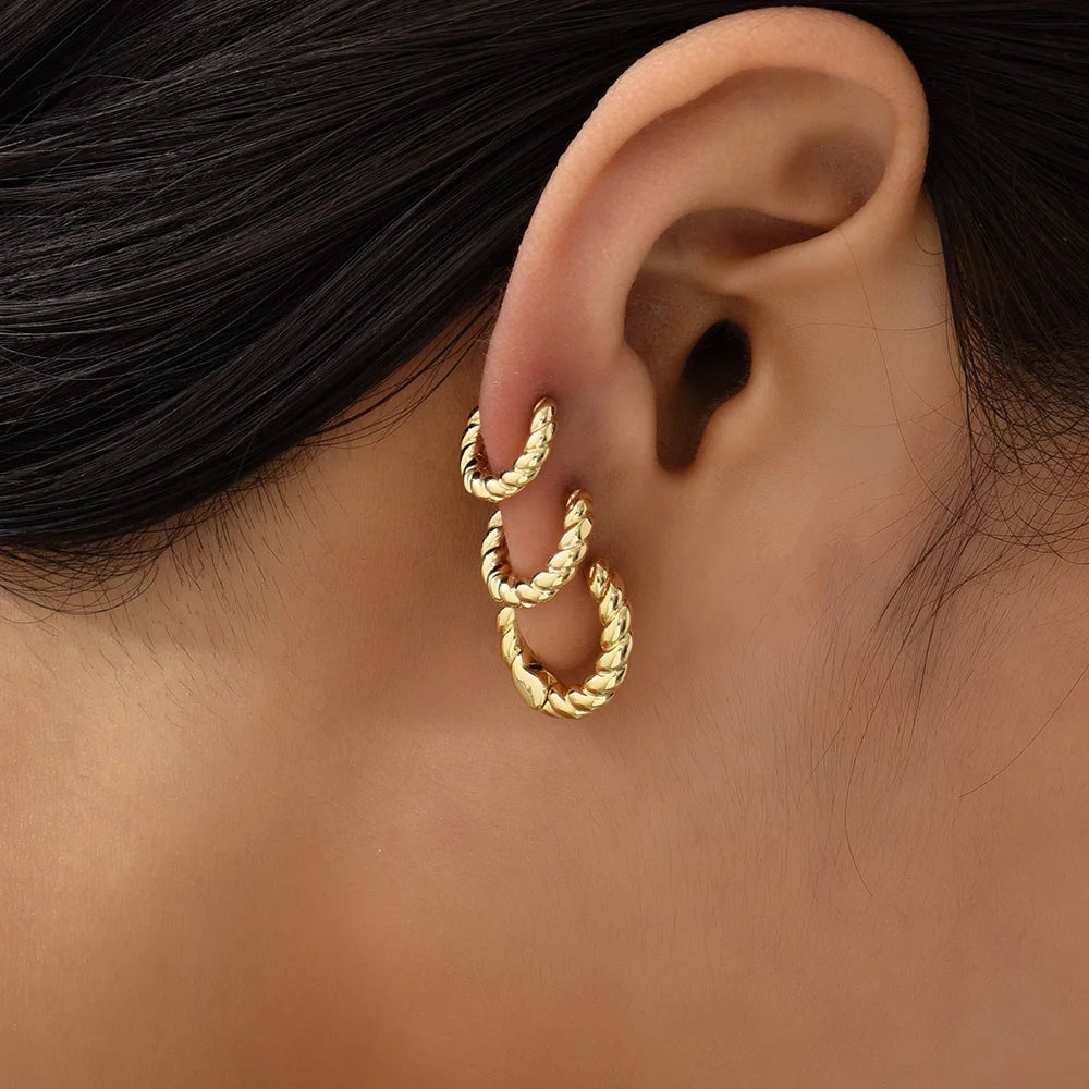 Gold hoop earrings worn by a person with dark hair.