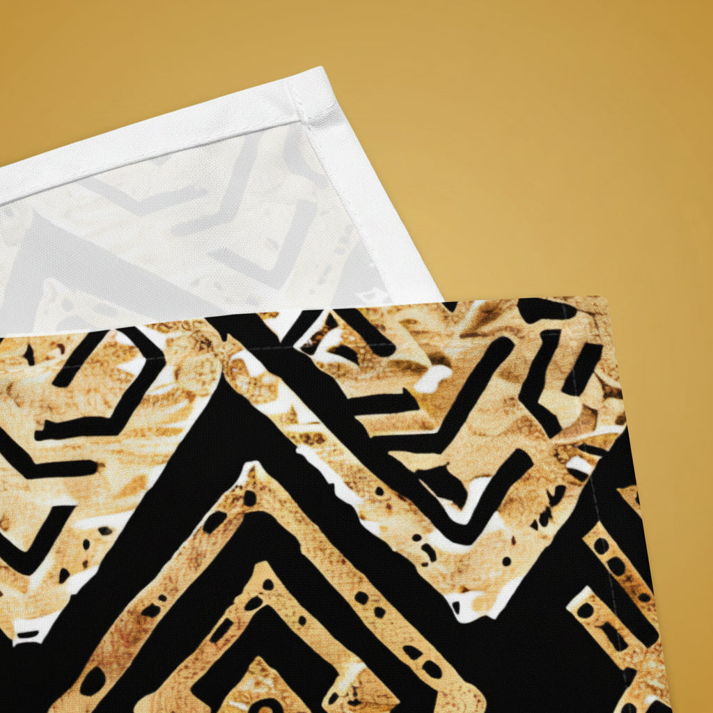 A close-up of a patterned textile or art print featuring a black and gold geometric maze-like design, with a translucent white backing sheet partially visible behind it on a white background.