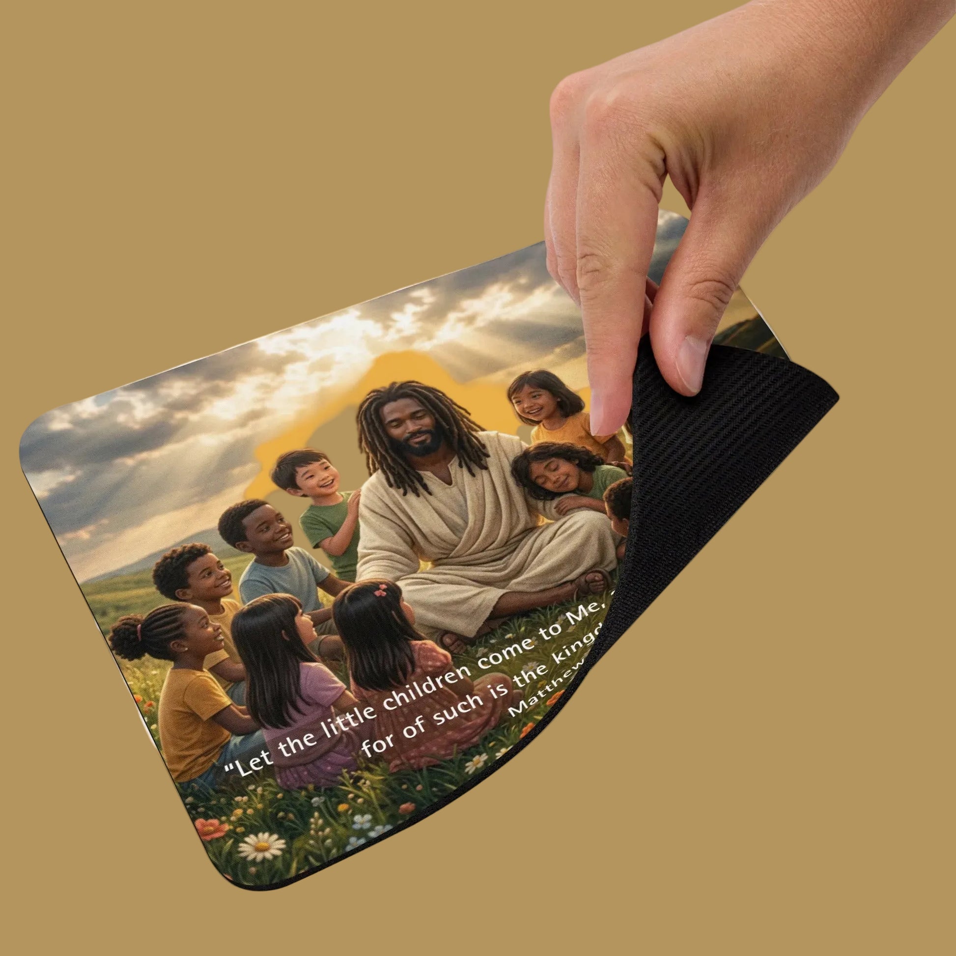 Hand holding a mouse pad with a religious illustration of Jesus and children on a beige background